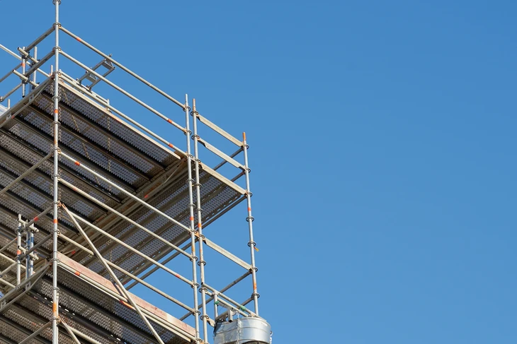 Chantier de construction extérieur avec échafaudage métallique tubulaire contre ciel bleu dégagé