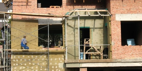 Ouvrier du bâtiment appliquant du plâtre sur les murs avec une truelle, présentant un savoir-faire artisanal dans la rénovation de la maison