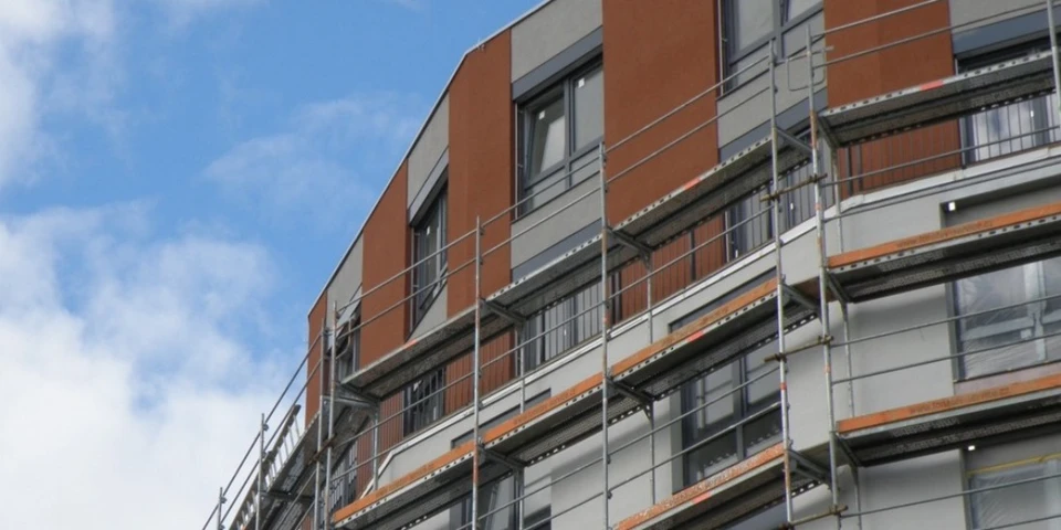 Véhicule utilitaire blanc stationné devant un bâtiment commercial avec façade vitrée et portes coulissantes
