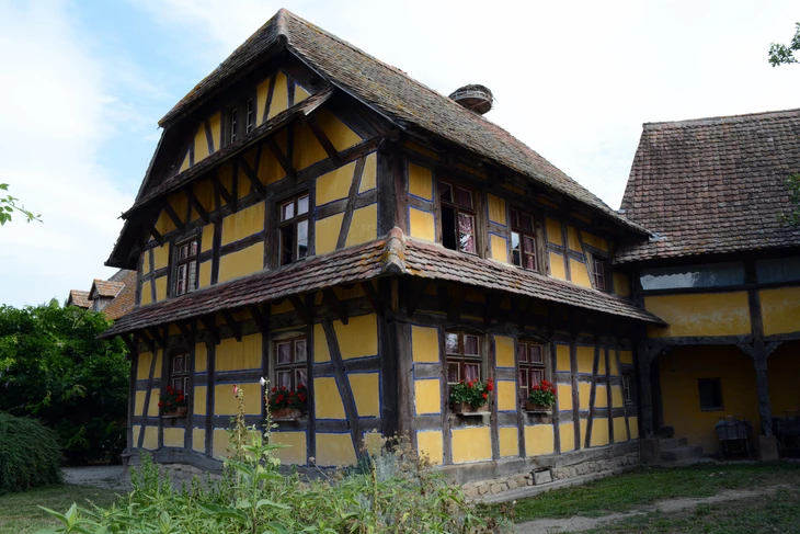 Maison à colombages alsacienne traditionnelle avec façade jaune ocre et pans de bois sombres