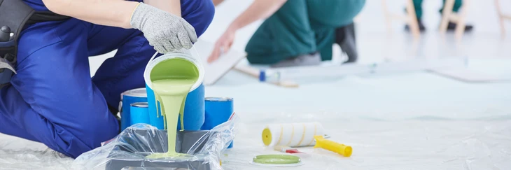Homme versant de la peinture murale verte dans un plateau de peinture, gros plan