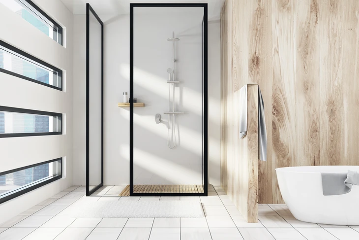 Une salle de bain blanche et en bois avec douche, une baignoire blanche et une fenêtre en forme originale