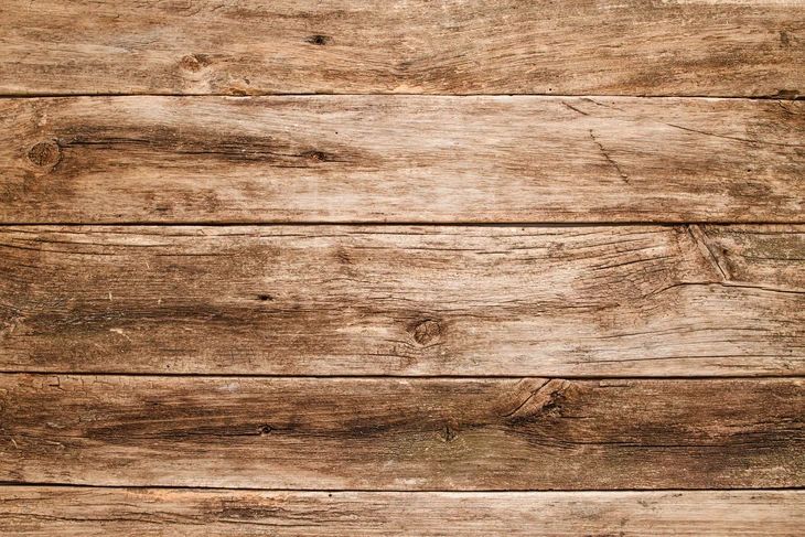 Planches de bois brut vieilli disposées horizontalement, surface extérieure patinée par les intempéries