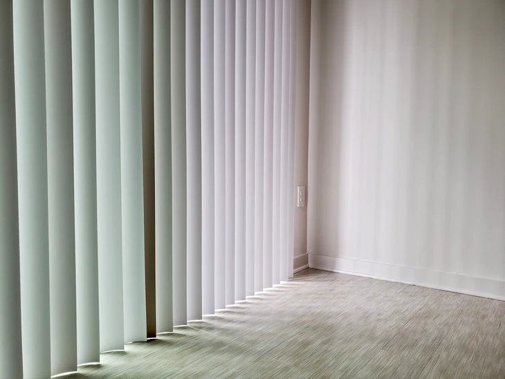 Intérieur moderne avec stores à lamelles verticales blanches filtrant la lumière naturelle