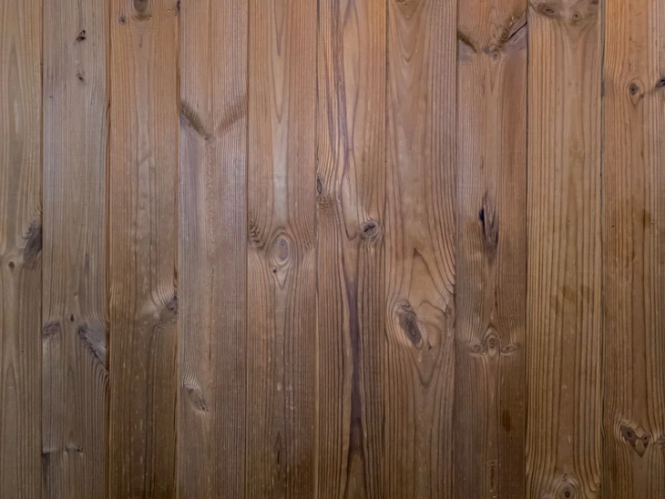 Planches de bois naturel disposées verticalement formant un lambris ou bardage